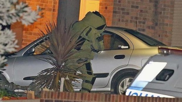 Bomb fears: A police officer in a special suit inspects the dead man's car at the scene on Tuesday night. 