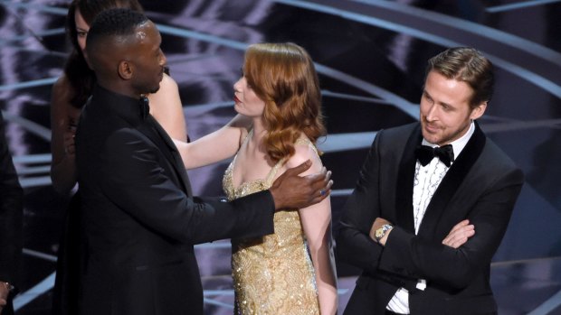 Ryan Gosling, right, stands with his arms folded as Emma Stone, centre, congratulates Mahershala Ali 