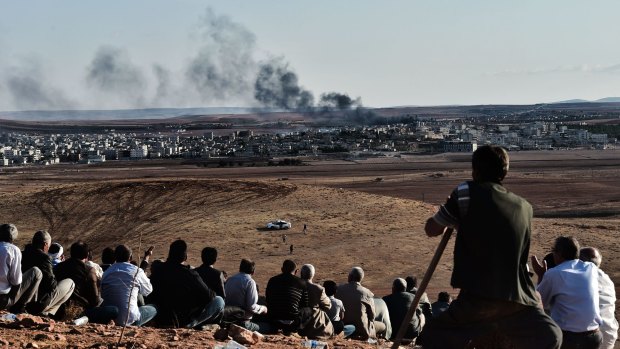 Kurdish people watch the battle for Kobane from a hill in neighbouring Turkey.