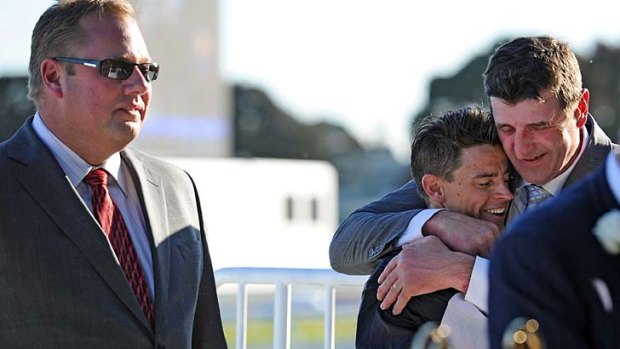 Owner Nick Williams looks on as trainer Robert Hickmott hugs Nicholas Hall after he rode Fawkner to victory in the Caulfield Cup.