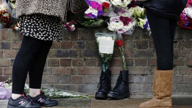 Tribute: People laying flowers stand near a pair of army boots and floral tributes for Drummer Lee Rigby.
