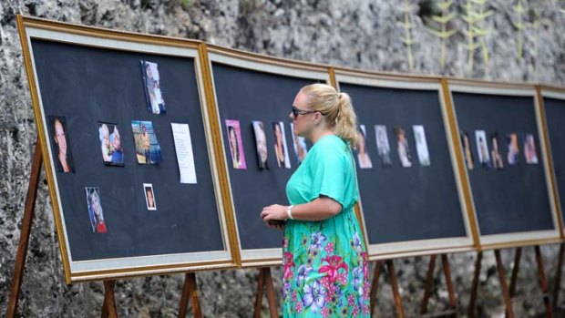 Emotional families and friends view a picture board of the victims of the Bali bombing attack at the official memorial service at Garuda Wisnu Kencana.