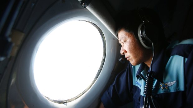 Military officer Nguyen Tran looks out from a Vietnam Air Force aircraft during an earlier mission to find MH370.