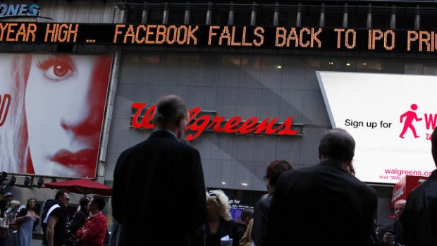 The Times Square news ticker displays a headline about the newly-debuted Facebook stock price.