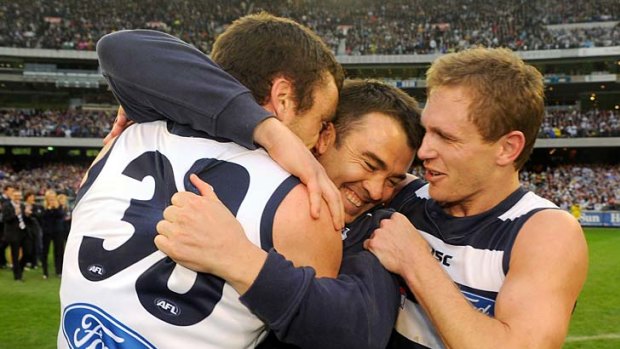 Caught in the middle: Coach Chris Scott gets a hug from Cats Matthew Scarlett (left) and Joel Selwood.