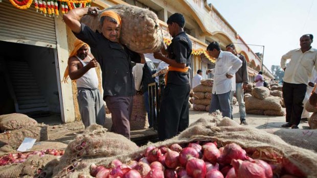 A worker carries a bag of onions at a wholesale market in Nashik, Maharashtra.