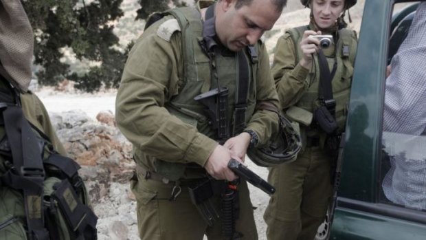 Israeli soldiers inspect pistols taken from Israeli settlers who entered the West Bank village of Burin on Monday.
