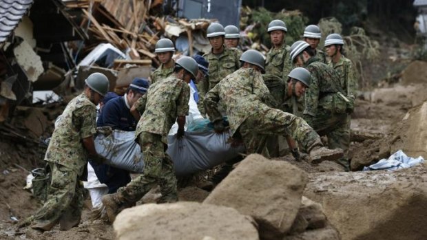 Japanese soldiers and police carry the body of a victim after the landslide swept through a residential area at Asaminami ward in Hiroshima, western Japan.