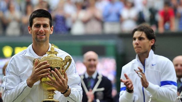 It's mine: Novak Djokovic grasps the Wimbledon trophy after his easy four-set victory over Rafael Nadal.