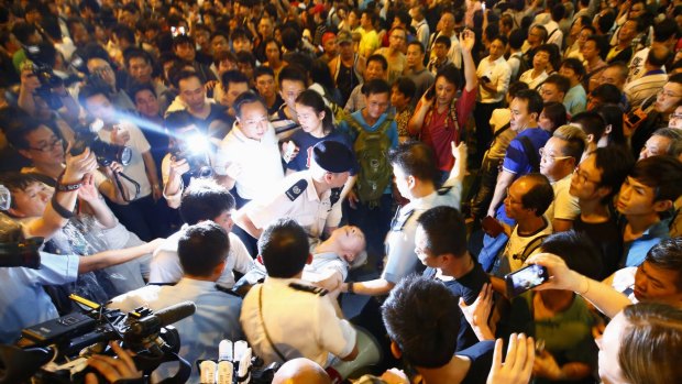 Police remove a man who collapsed during confrontations between anti-Occupy Central protesters and pro-democracy protesters on a main street at Hong Kong's Mongkok shopping district.