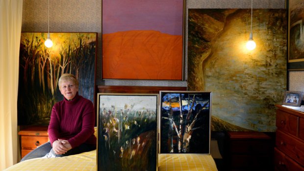 Joy Herman with painting by her late brother, the artist, antiques dealer and teacher John Brock.