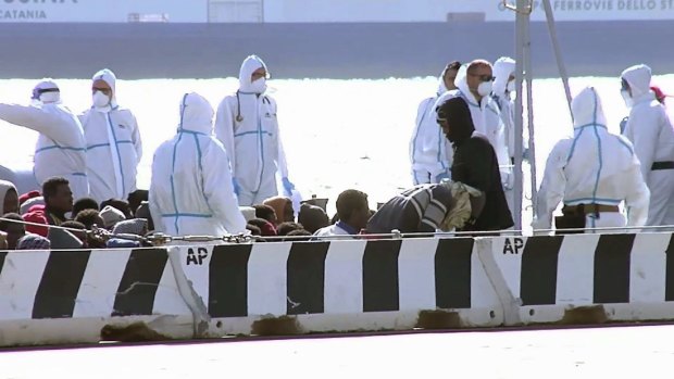 Sitting asylum-seekers, surrounded by emergency relief workers at the Italian port of Messina on Saturday. 