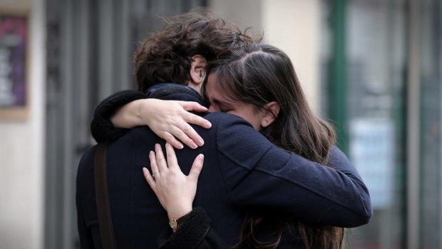 A couple embrace after laying flowers at the La Belle Equipe cafe in Paris.