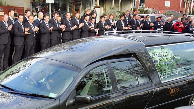 Geelong players form a guard of honour as the hearse leaves after Bob Davis' funeral.