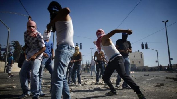 Palestinian protesters throw stones towards Israeli police.