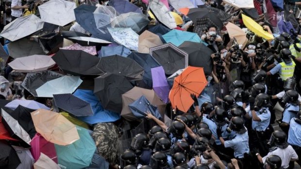 Makeshift shield: Protesters hold up umbrellas to try to protect themselves from tear-gas as pro-democracy demonstrators bring parts of central Hong Kong to a standstill. 