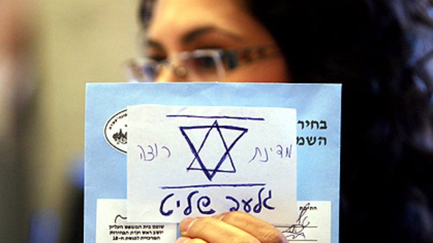 An Israeli election official holds up an invalid general election ballot with a note glued to it that reads in Hebrew: "The State of Israel wants Gilad Shalit", referring to the Israeli soldier captured by Hamas in 2006.