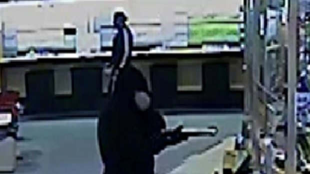 Frightening ... A man is caught on CCTV pointing a weapon at a cashier.