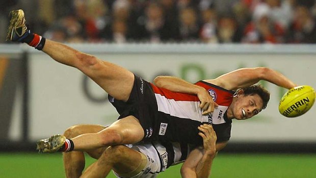 Jack Steven of the Saints is tackled by Joel Corey of the Cats.