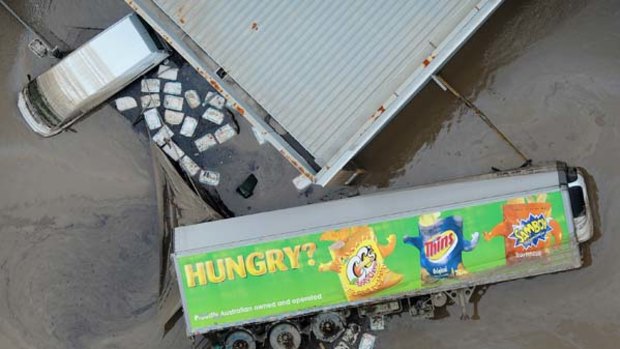 A food transport trailer lays on its side in mud as the floodwaters recede in the Brisbane industrial area of Rocklea on January 14.