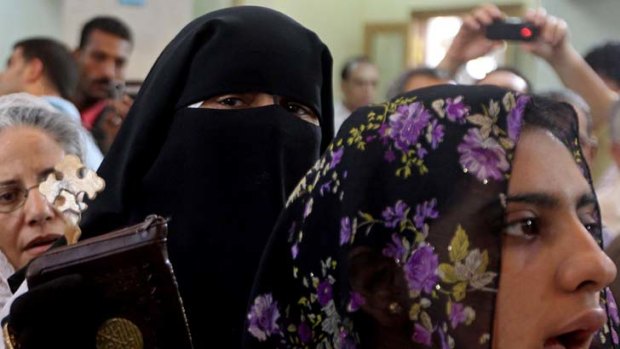 A woman holds a cross and the Koran at St Mary's Church in Cairo.