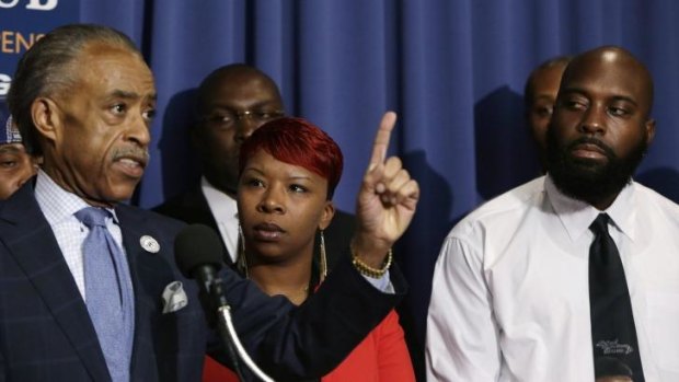 US civil rights leader Reverend Al Sharpton speaks next to the parents of Michael Brown, Lesley McSpadden and Michael Brown Sr., at a news conference.