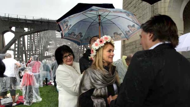 Surprise wedding ... a friend keeps Mira Brodka dry as she marries John Goldbrough on the Harbour Bridge yesterday.