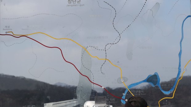 A visitor watches the north side through the glass showing a map of the border area between North and South Koreas at the Imjingak Pavilion in Paju.