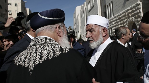 Sephardi Chief Rabbi of Israel Shlomo Amar (left) shakes hands with Arab-Israeli Sheikh Mohammed Kiwan during a visit by chief clerics and representatives of different religious communities to the synagogue where two Palestinians killed five Israelis in Jerusalem the previous day.