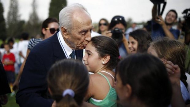 Peace effort ... Former Israeli president Shimon Peres kisses a girl during an event opening the training year of an Israeli-Palestinian soccer program launched by the Peres Centre for Peace, in Kibbutz Dorot, outside the Gaza Strip.