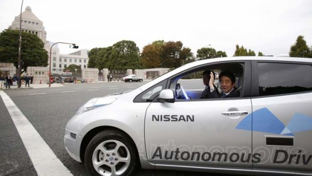 "World's best": Shinzo Abe passes the Diet building in a self-driving Nissan on Saturday.