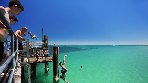 A teengager jumps off the Glenelg jetty during a heat wave in Adelaide in January 2014