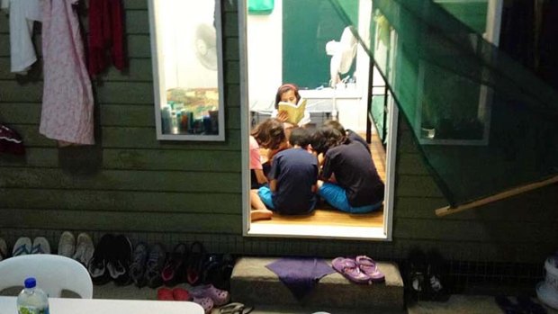 Hot boxes &#8230; a family reads together inside one of the wooden dongas.