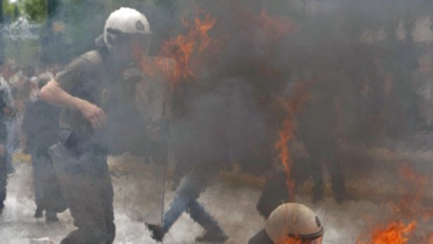A riot policeman falls after being hit with molotov cocktail near the Greek parliament in Athens during a nationwide strike in Greece.