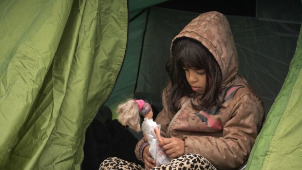 A girl plays with a doll at the northern Greek border station of Idomeni.