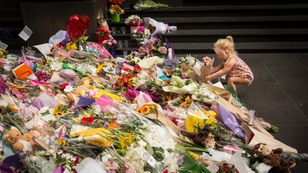 Two-year-old Jesse lays flowers at the tribute to the Bourke Street victims in Melbourne.