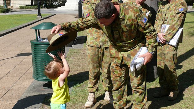 Soldiers take a break from fundraising to play with a young civilian.