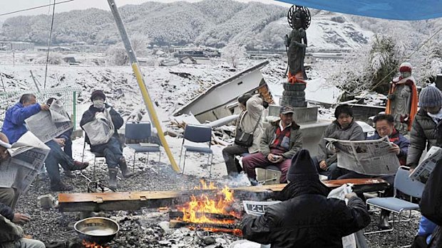 Earthquake and tsunami survivors gather to read newspapers in Otsuchi, northern Japan, yesterday.