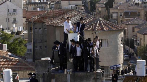 Ultra-Orthodox Jewish youths stand atop a roof as they wait for the body of Rabbi Ovadia Yosef to be brought to a seminary before his funeral in Jerusalem.