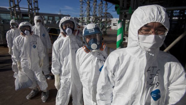 Workers in protective suits and masks wait to enter the emergency operation center at the Fukushima Dai-ichi nuclear power station.