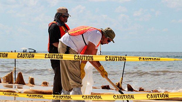 Huge job ahead: Workers remove oil residue washed ashore in Orange Beach, Alabama.