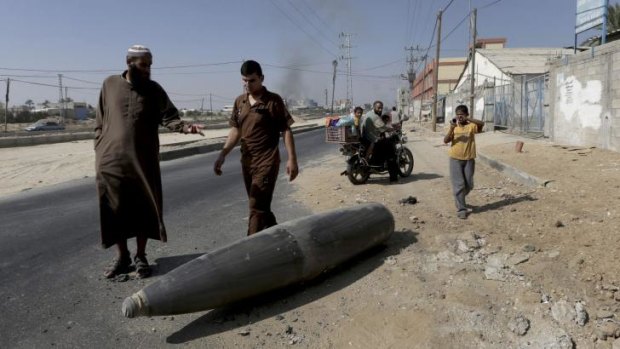 Pedestrians inspect an Israeli fighter jet external fuel tank, known as drop tank, on a main road in Deir al-Balah, central Gaza.