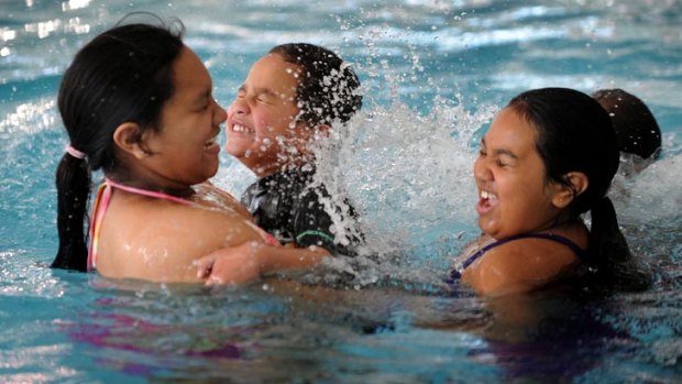 Swim programs ... Tahlia Jard, 10, holds her brother Roderick as sister Alyssa plays in the pool.