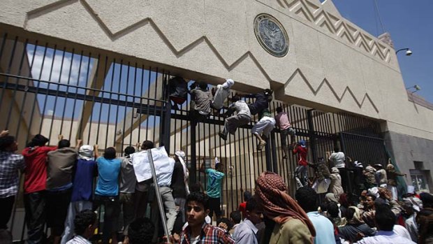 Outrage ... Yemeni protesters climb the gate of the US embassy during a protestt about a film in a Sanaa yesterday.