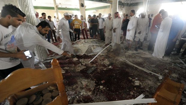 Saudi men gather around debris following a blast inside a mosque, in the mainly Shiite Saudi Gulf coastal town of al-Qadeeh. A suicide bomber targeted a Shiite mosque during Friday prayers.