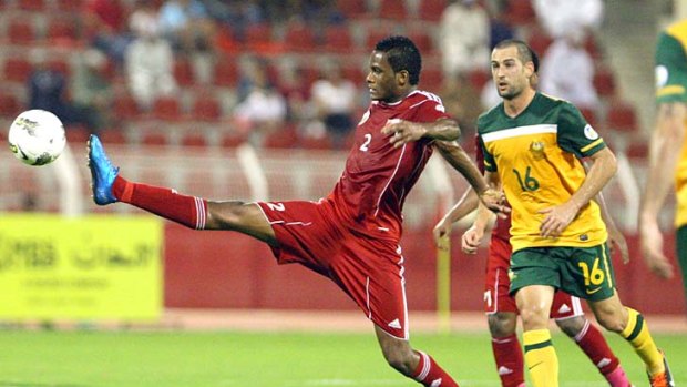 Omani player Eid al-Farsi takes control watched by Socceroo Carl Valeri.