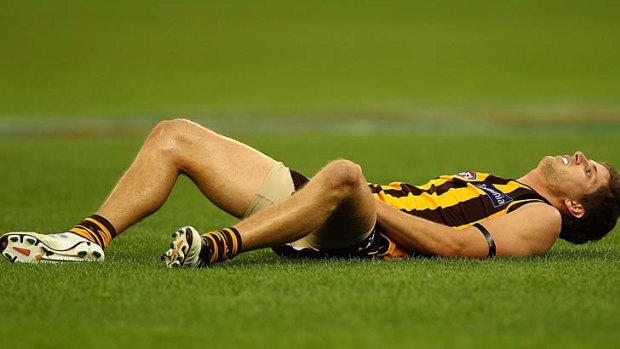 Hawk Luke Breust lies on the turf after being knocked out following a collision with Brodie Martin of the Crows.