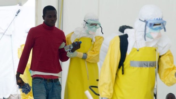 Health workers, wearing protective equipment, arrive with a potentially contaminated patient in Monrovia.