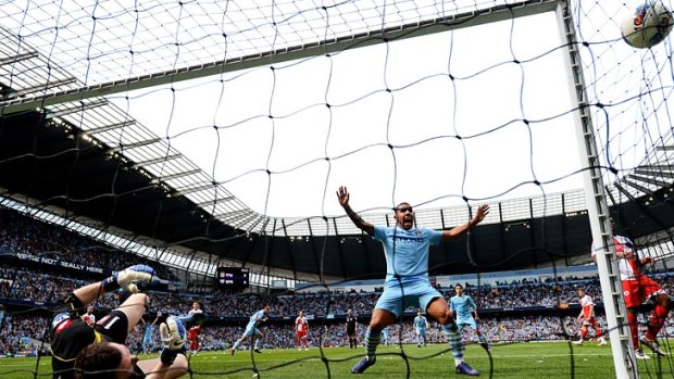 Carlos Tevez of Manchester City celebrates as a shot from teammate Pablo Zabaleta beats goalkeeper Paddy Kenny of QPR for the opening goal.