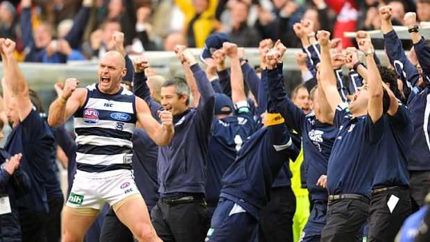 It's ours: The Geelong bench, with Josh Hunt at the front, stands and cheers at the final siren.